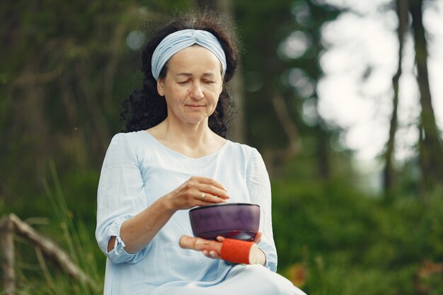 Femme âgée avec des choses hindoues. Dame en robe bleue. Brunette assise.