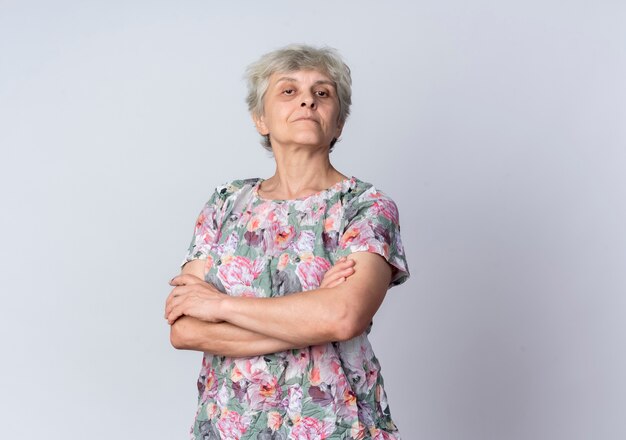 Femme âgée confiante croise les bras et regarde isolé sur un mur blanc