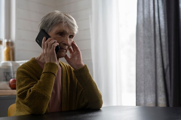 Femme âgée de coup moyen parlant au téléphone