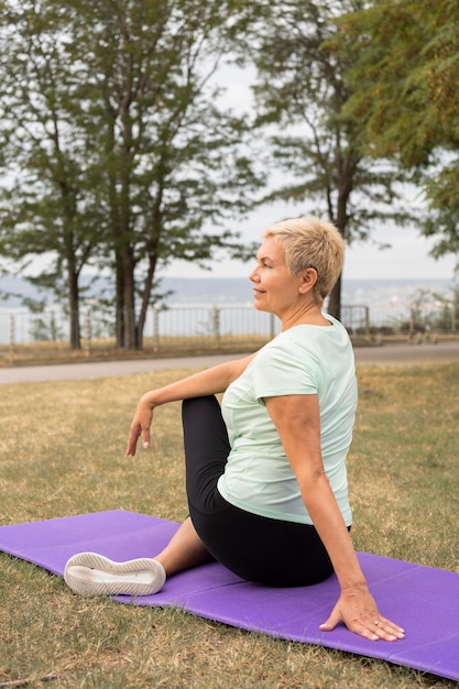 Femme âgée faisant du yoga à l'extérieur dans le parc