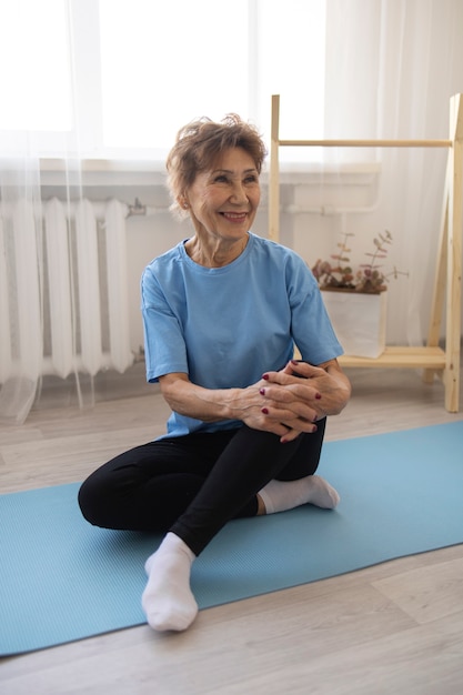 Femme âgée faisant du yoga à la maison