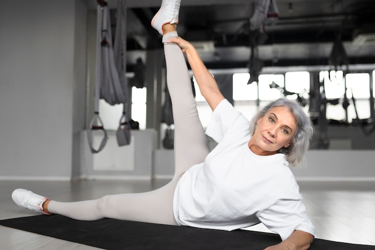 Photo gratuit femme âgée faisant du yoga sur un tapis de yoga dans la salle de sport