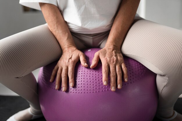 Femme âgée faisant une séance d'entraînement de ballon de gymnastique au gymnase