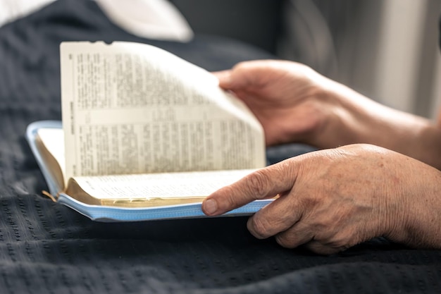 Une femme âgée lit un livre de la bible mains et gros plan