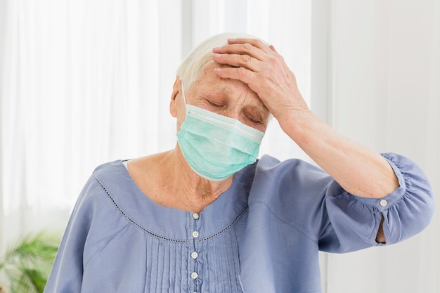 Femme âgée avec un masque médical mal au cœur