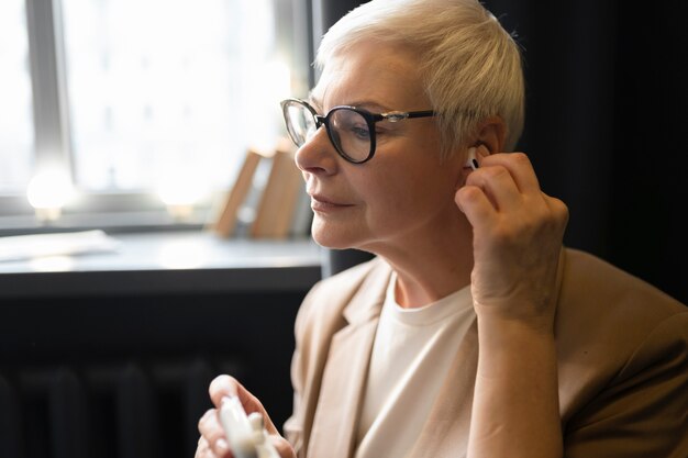 Femme âgée mettant ses écouteurs dans ses oreilles dans un café