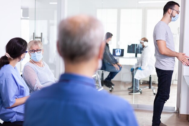 Femme âgée portant un masque facial comme précaution de sécurité contre le coronavirus pendant la pandémie mondiale avec le coronavirus dans la salle d'attente de l'hôpital