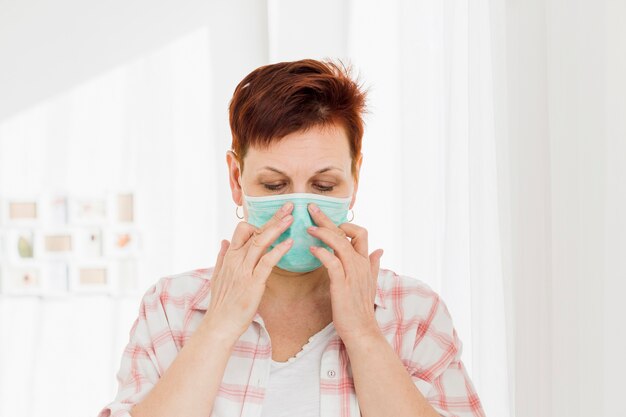 Femme âgée portant un masque médical à la maison