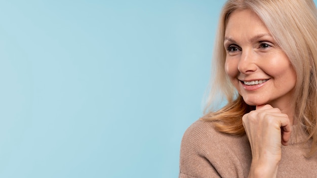 Femme âgée posant et souriant sur un fond bleu