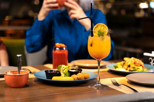 Femme âgée prenant des photos de nourriture et de boissons au restaurant