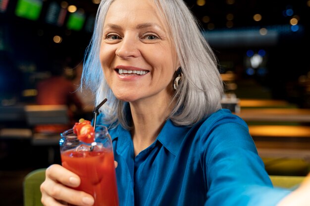 Femme âgée prenant un selfie avec son verre dans un restaurant
