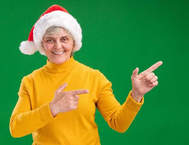 Femme âgée souriante avec Bonnet de Noel pointant sur le côté