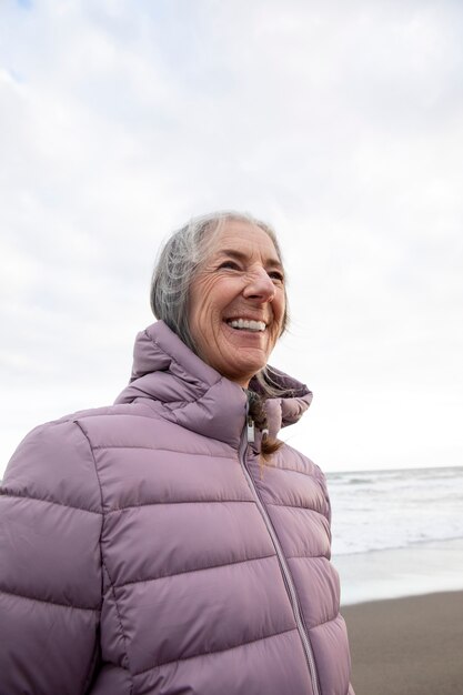 Femme âgée souriante à coup moyen au bord de la mer