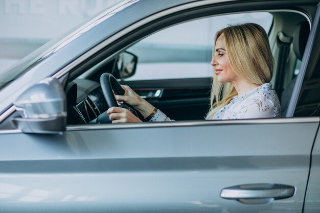 Femme âgée testant une voiture dans une salle d'exposition automobile