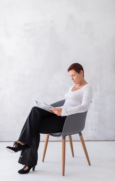 Femme âgée vue de face, lisant un magazine