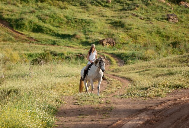 Femme agricultrice équitation dans la nature