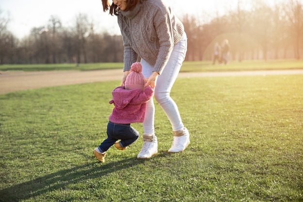 Femme aidant un enfant à marcher à l'extérieur