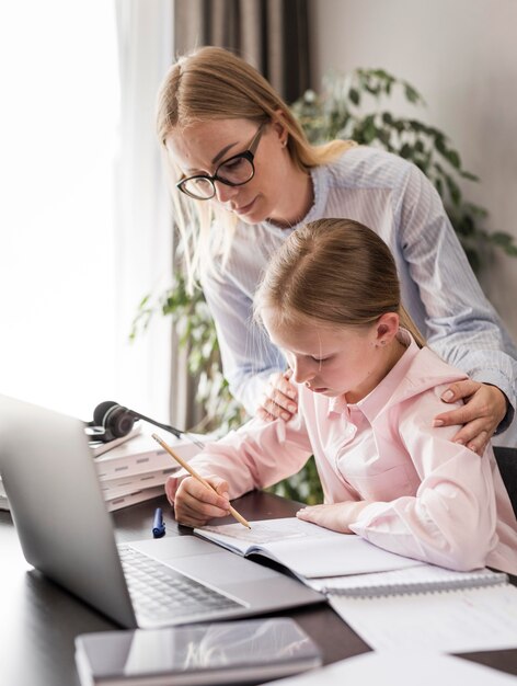 Femme aidant une petite fille à faire ses devoirs