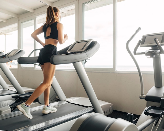 Femme à l'aide du tapis roulant à la salle de sport