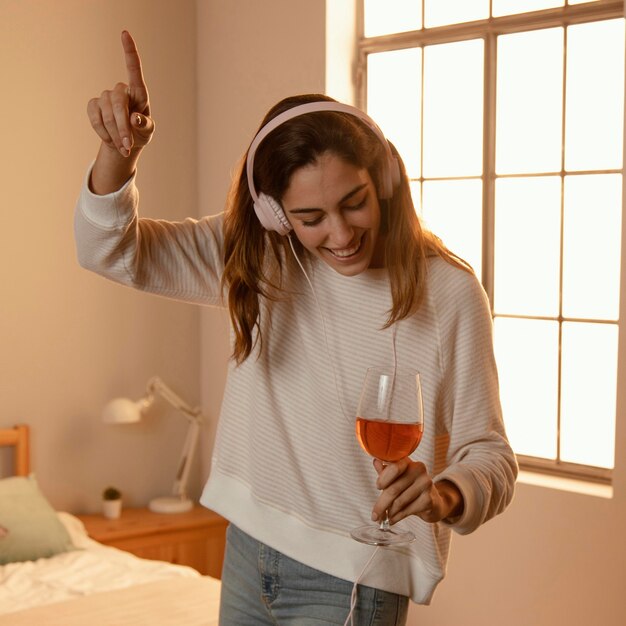 Femme à l'aide d'écouteurs pour la musique à la maison et boire