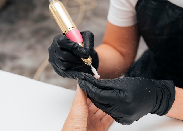 Femme à l'aide d'une lime à ongles sur le client et portant des gants