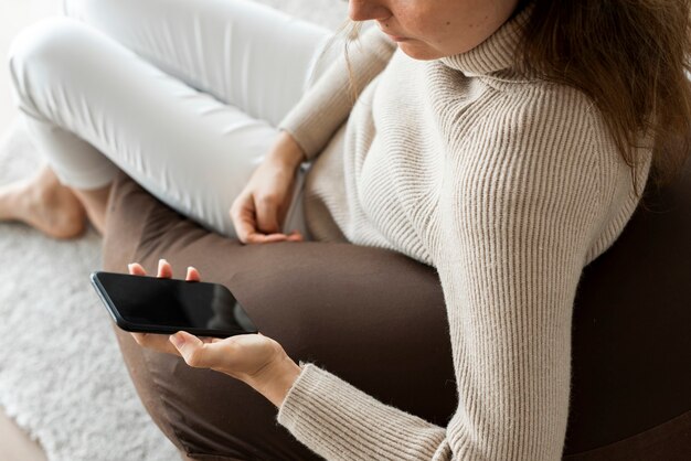 Femme à l'aide de smartphone sur un canapé