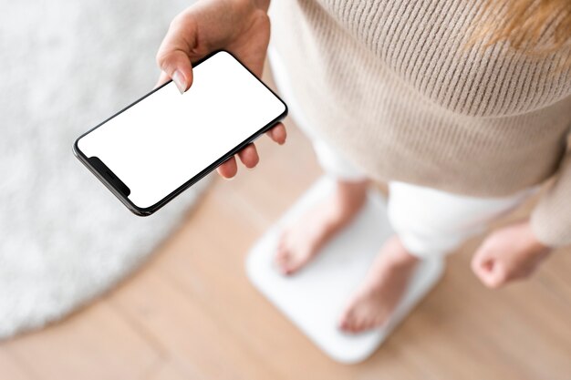 Femme à l'aide de smartphone à côté de la technologie innovante de balance de pesage