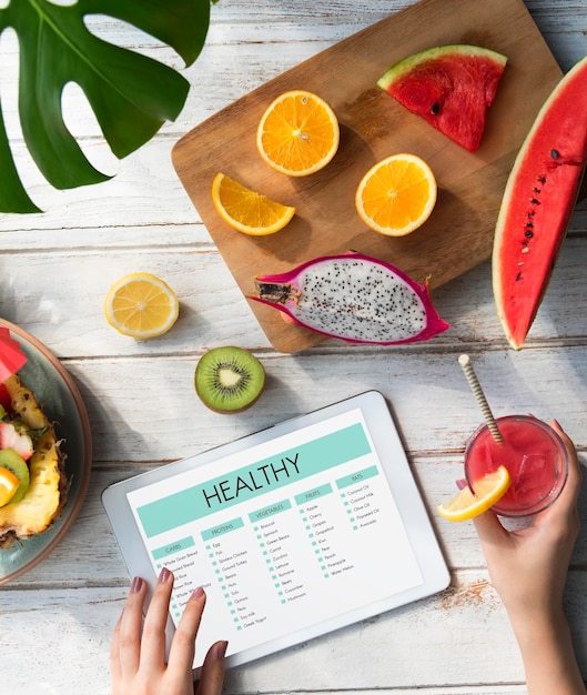 Photo gratuite femme à l'aide d'une tablette avec mise à plat de fruits d'été