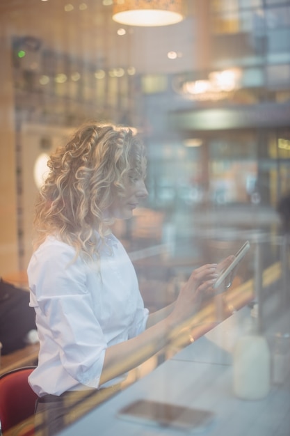 Femme à l'aide de tablette numérique au comptoir