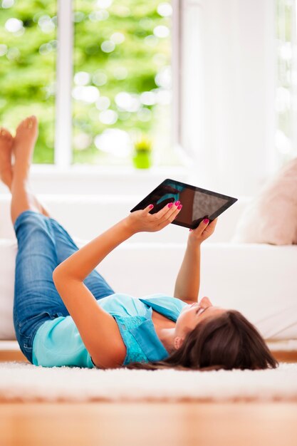 Femme à l'aide de tablette numérique à la maison