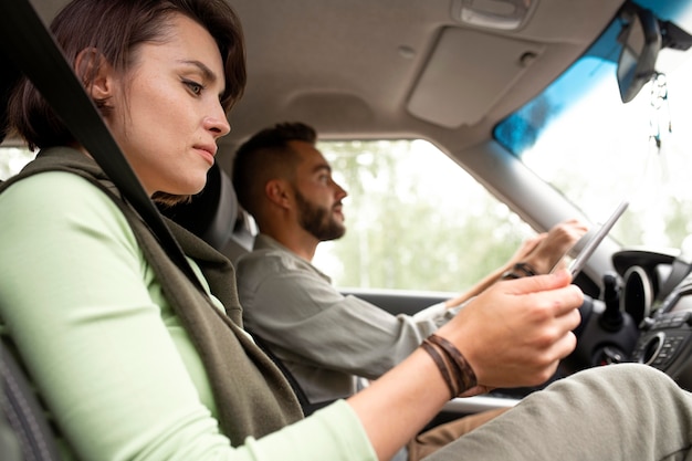 Femme à l'aide de tablette pendant que son petit ami conduit