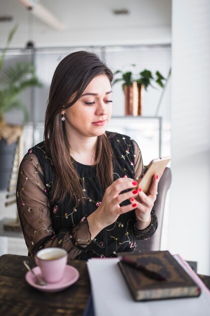 Femme à l&#39;aide de téléphone portable dans un café