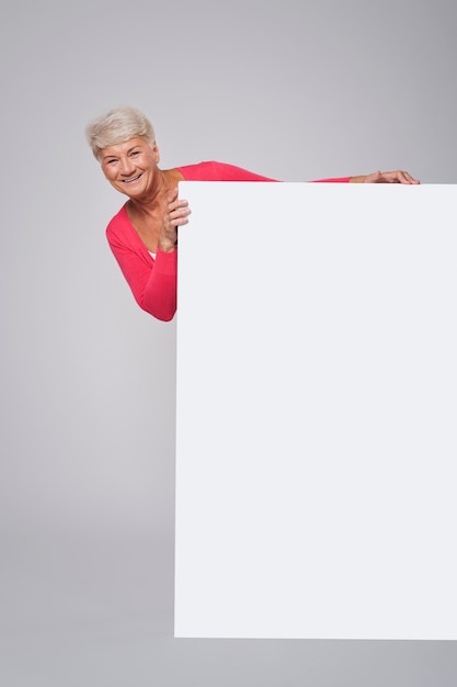 Photo gratuite femme aînée, debout, derrière, de, panneau blanc