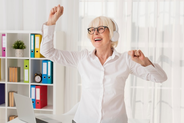 Femme aînée écoutant de la musique dans son bureau