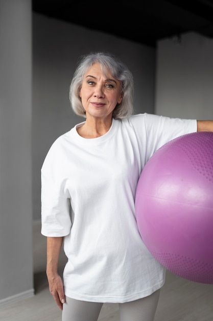 Photo gratuite femme aînée faisant des exercices de boule de gymnastique au gymnase