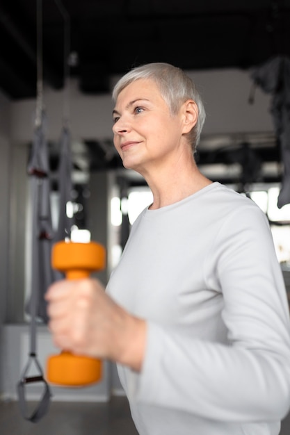 Femme aînée faisant des exercices d'haltères au gymnase