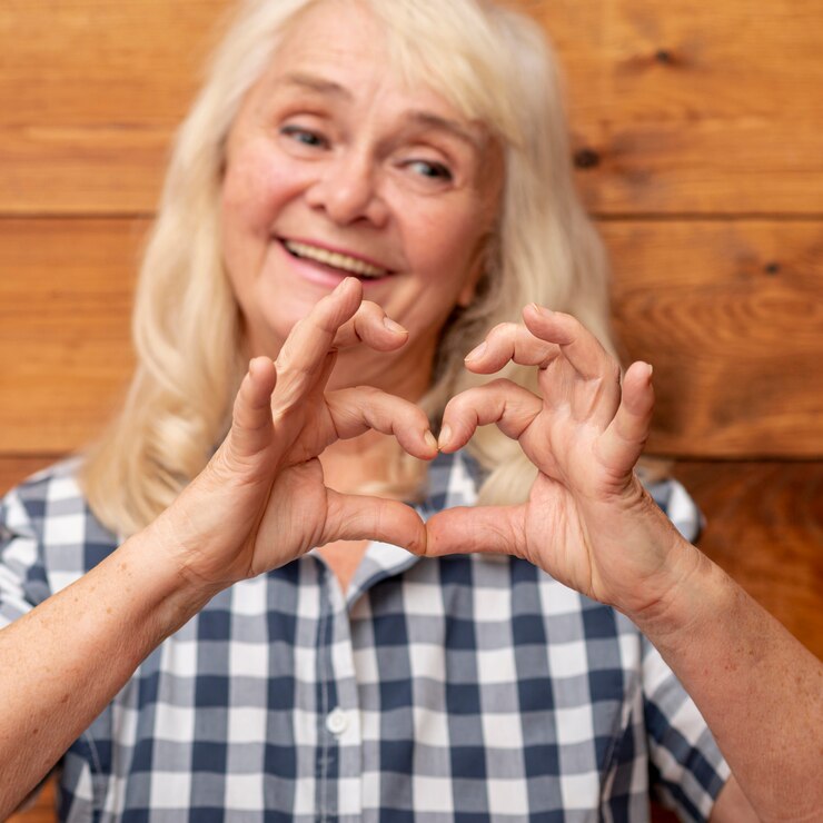 Photo gratuit femme aînée montrant la forme de coeur de la main