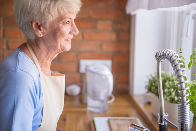 Photo gratuite femme aînée, regarder travers, les, fenêtre cuisine