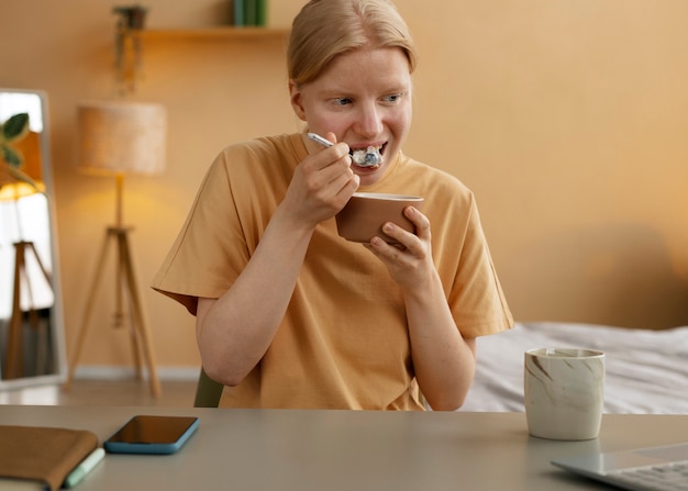 Photo gratuite femme albinos à coup moyen prenant son petit déjeuner