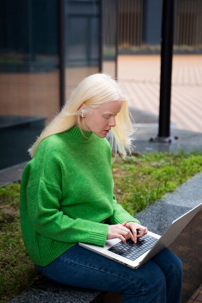 Femme albinos à coup moyen travaillant avec un ordinateur portable