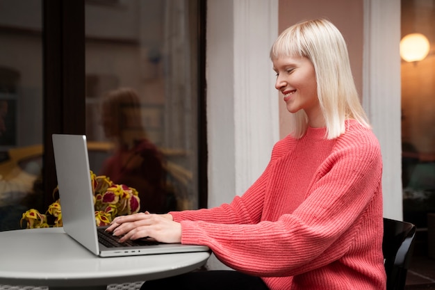 Femme albinos à coup moyen travaillant avec un ordinateur portable