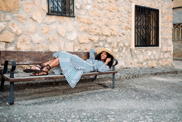 Femme allongée sur une chaise près d'une maison en pierre dans un village