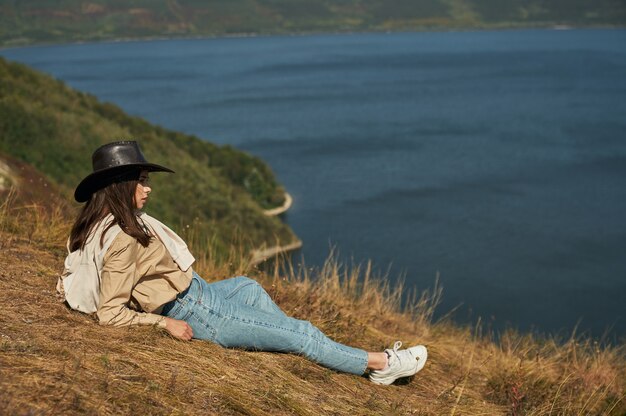 Femme allongée sur une haute colline et profitant d'un paysage pittoresque