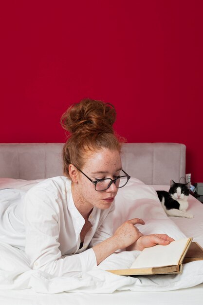 Femme allongée sur le lit avec un chat qui lit