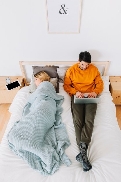 Femme allongée près d&#39;un homme avec un ordinateur portable