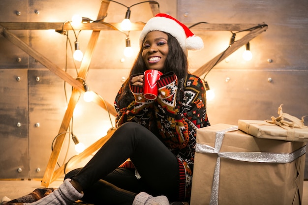 Femme américaine afro, boire du café un soir de Noël