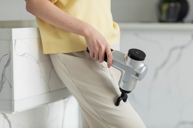 Femme à angle élevé à l'aide d'un pistolet de massage