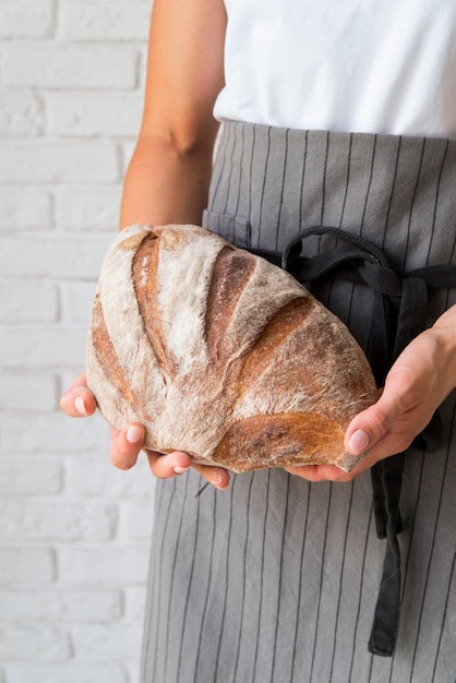 Femme à angle élevé tenant une miche de pain