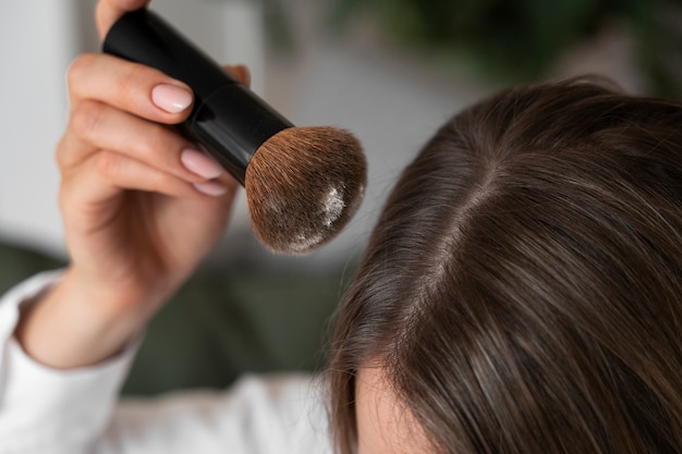 Femme à angle élevé utilisant du shampoing sec à la maison