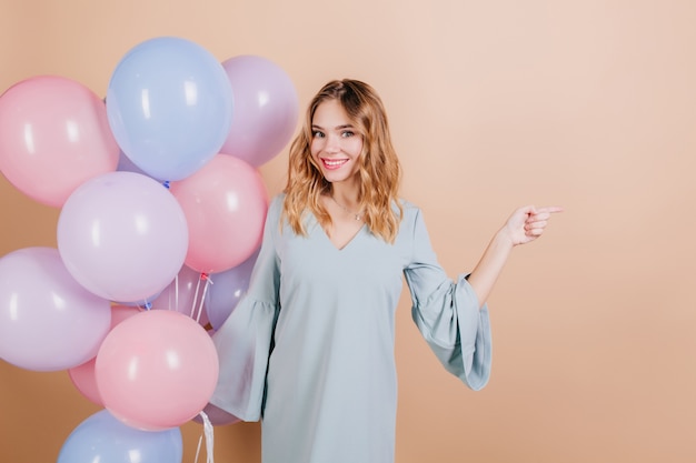 Femme d'anniversaire blanche inspirée posant avec des ballons d'hélium